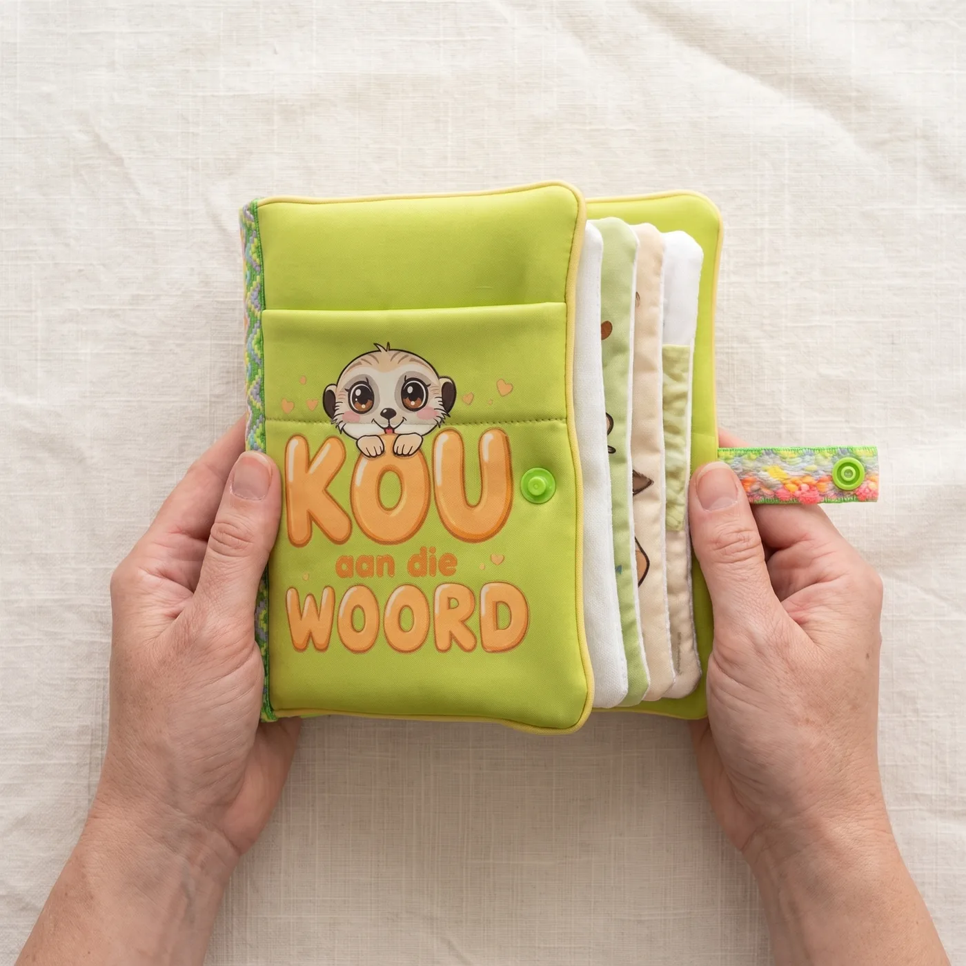 Two hands holding the Baby Bible, the cover reading Kou aan die Woord